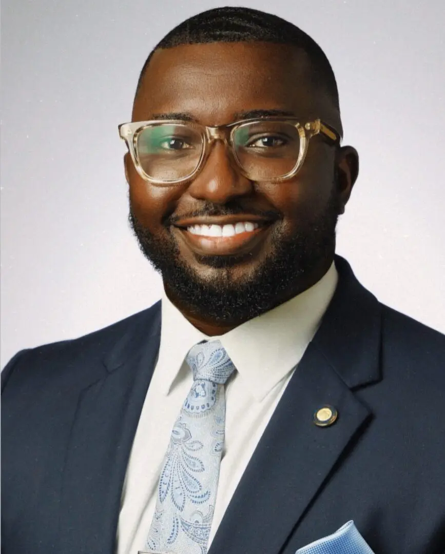 Smiling person in glasses, suit, patterned tie